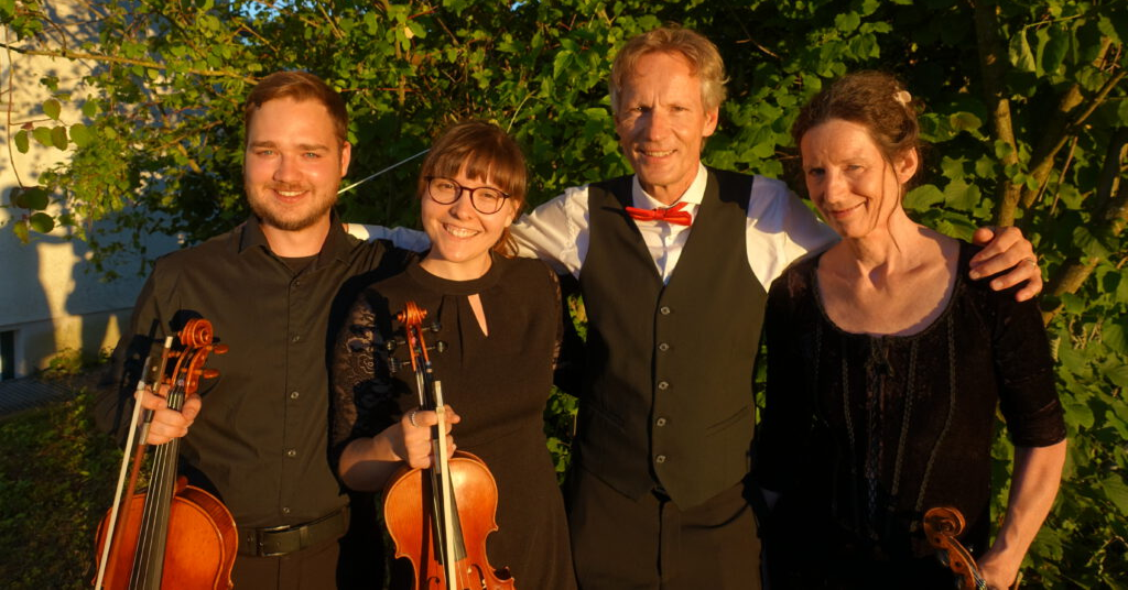 Vier Personen vor einem Baum